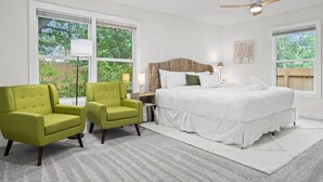 A bedroom with a bed, two green armchairs, a ceiling fan, and large windows. - Game, Grill & Lounge Modern S Austin Hangout House Sleeps 10 - Mins to SoCo (Austin)