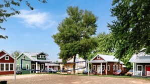 A row of single-story houses with a volleyball net in the middle, surrounded by trees and a clear sky.