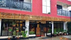 A two-story building with a red facade, a 'Bamboo Restaurant' sign, and potted plants in front. - Nomads cafe (Eldoret)
