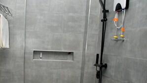 A modern bathroom with grey tiles, a shower, a toilet, and a towel rack. - Nomads cafe (Eldoret)