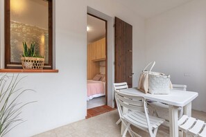 Ein Zimmer mit einem Bett, einem Tisch mit Stühlen, einem Korb mit Pflanzen und einer Holztür.