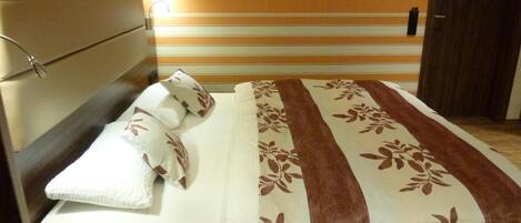 Una habitación de hotel con una cama, una mesita de noche, una lámpara de pared y un cuadro en la pared.