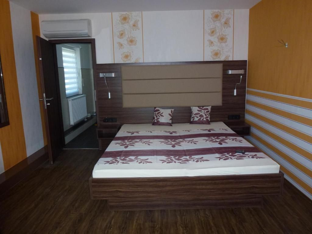 A bedroom with a wooden headboard, a bed with a floral bedspread, and a door leading to a hallway.