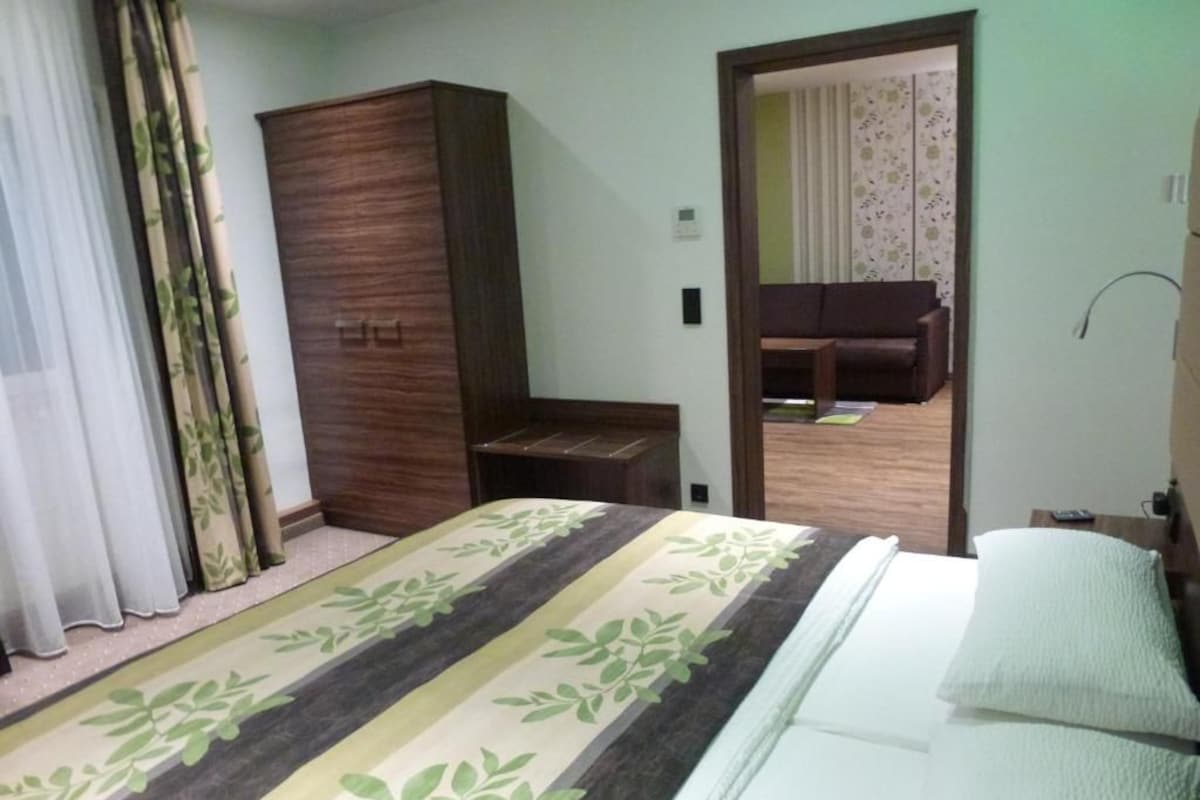 A bedroom with a bed, a wardrobe, a small table, and a mirror.