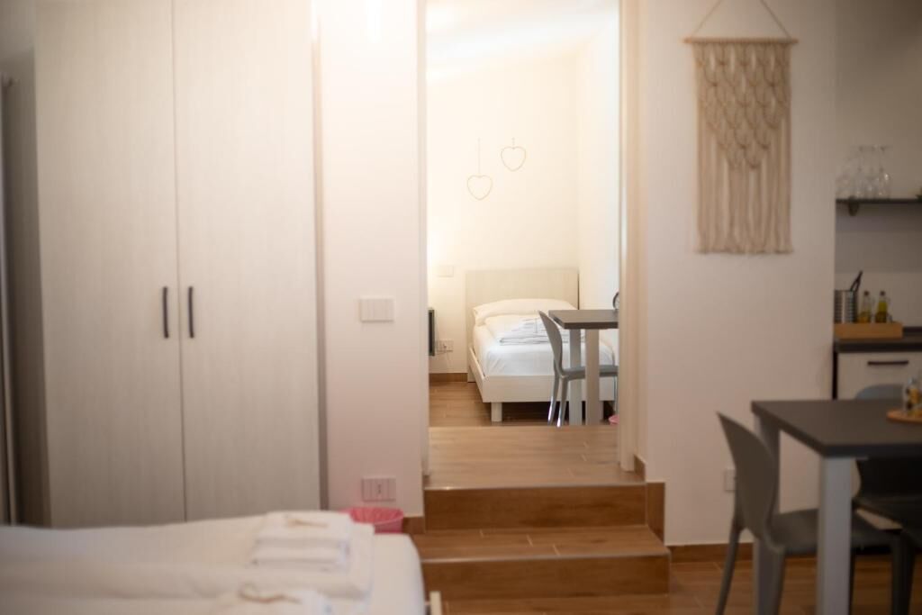 A bedroom with a bed, a desk, and a chair. There is a staircase leading to another room.