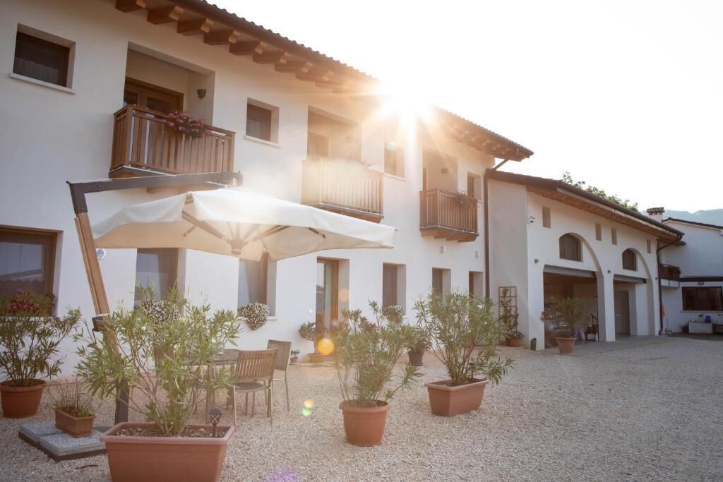 A building with a courtyard, potted plants, outdoor furniture, and a white umbrella.