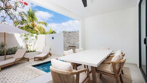 Un patio moderno al aire libre con piscina, sillas de descanso y una mesa de comedor.