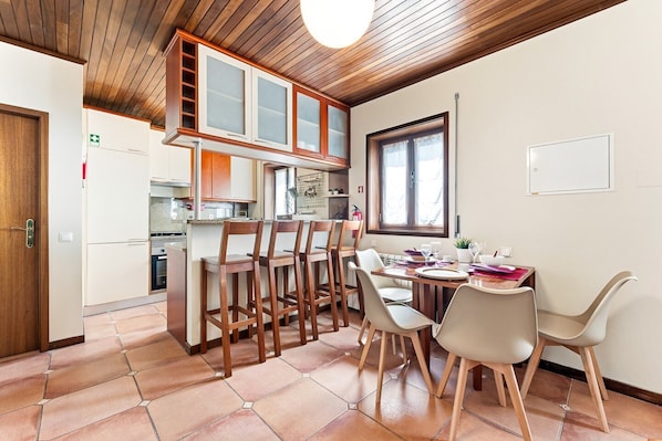 A kitchen with wooden cabinets, a dining table with chairs, and a window.