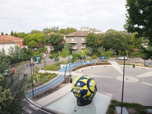 A roundabout with a yellow and blue sports ball sculpture, surrounded by greenery and residential buildings. - Superior City View Suite (Pesaro)