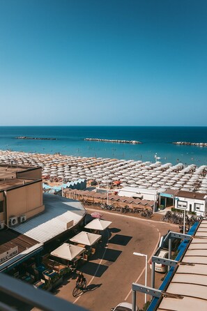 A beachside view with umbrellas, a restaurant, and a pier. - Superior City View Suite (Pesaro)