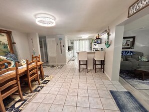 A dining area with a wooden table and chairs, a kitchen with a bar, and a living area with a couch. - 2-bedroom house w/pool in the heart of old Homosassa! (Homosassa)