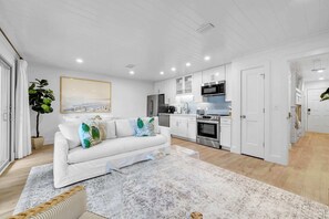 A modern kitchen with white cabinetry, stainless steel appliances, and a dining area with a white table and chairs. - Saltwater Society by Stay on 30a (Inlet Beach)