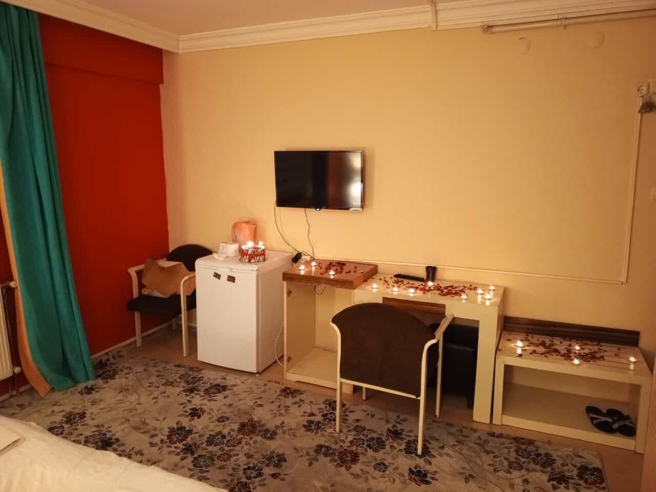 Una habitación de hotel con cama, escritorio, silla, televisor y refrigerador pequeño.