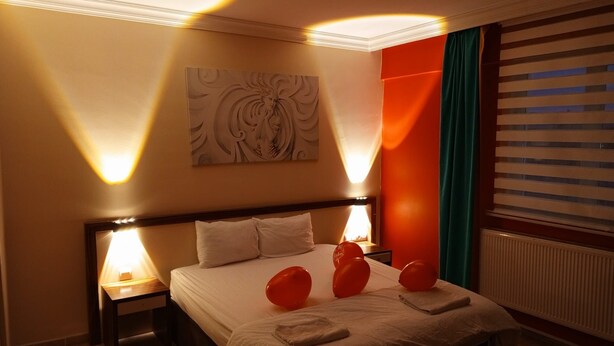 Una habitación de hotel con una cama grande, dos lámparas de noche, una obra de arte en la pared y una ventana con persianas.