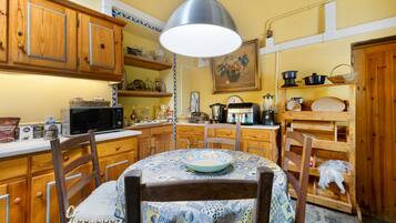 Una cocina con armarios de madera, microondas, cafetera y una mesa de comedor con sillas.
