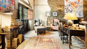 Une pièce chaleureuse avec un mur en pierre, un tapis à motifs et un mélange de meubles anciens et modernes.