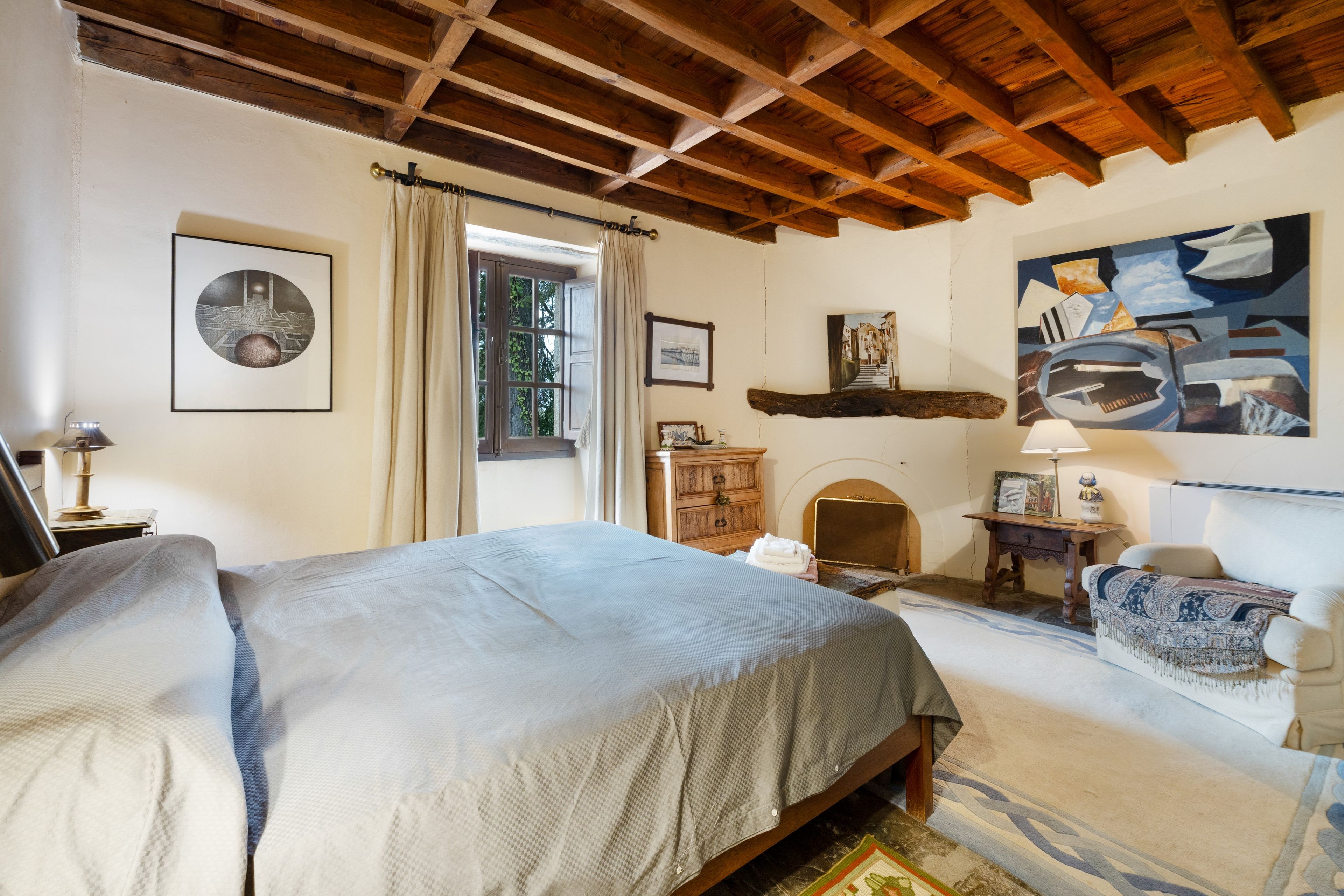 Un dormitorio con cama, cómoda, silla y un cuadro en la pared.