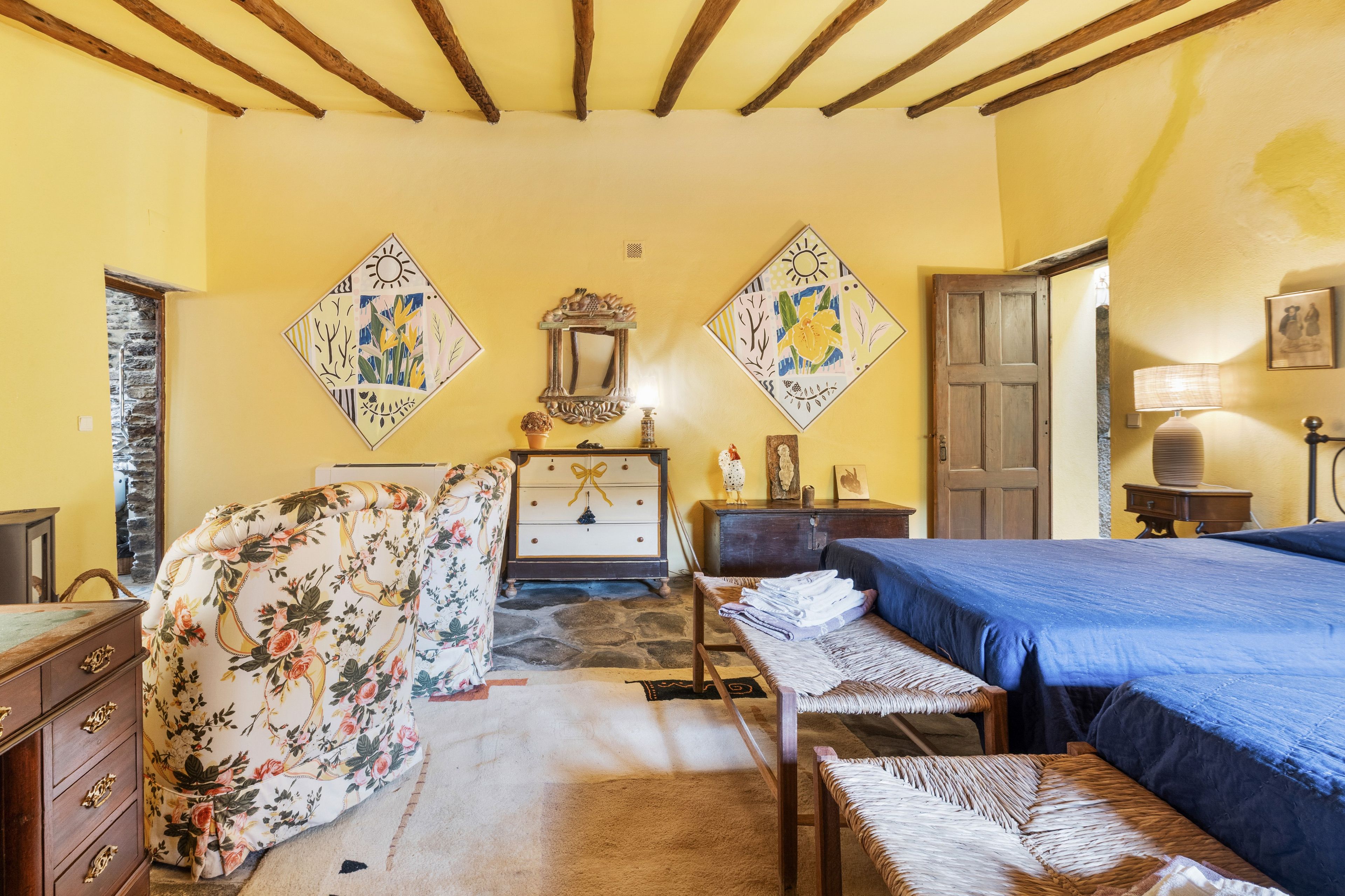 Un dormitorio con cama, cómoda, silla, mesa y espejo.