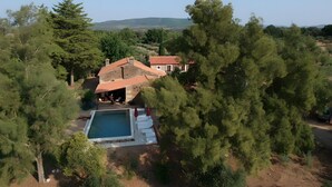 Una casa rodeada de árboles y colinas, con piscina.