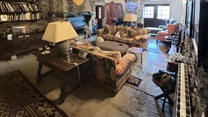 Un interior rústico con paredes de piedra vista, vigas de madera, chimenea y un piano.