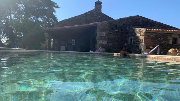 Una piscina cristalina con un edificio de piedra al fondo.