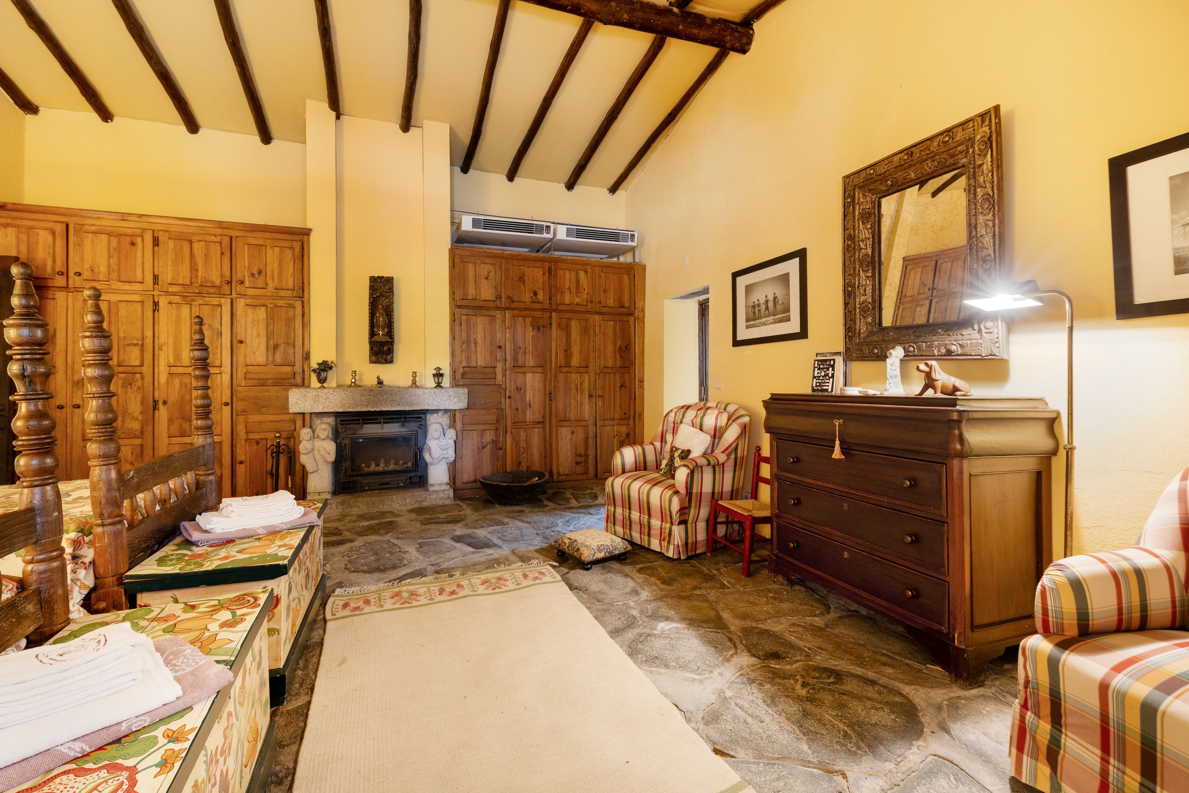 Habitación tradicional con chimenea, muebles de madera y piso de piedra.