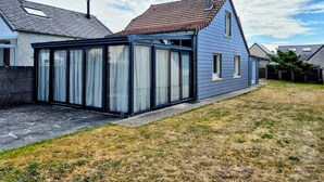 Una casa con veranda, tetto in tegole e giardino con prato.