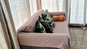 Una stanza con un letto, una piccola zona salotto e tende.