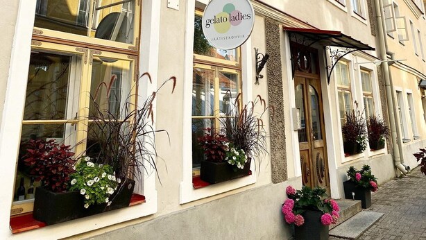 Un edificio con un letrero que dice 'gelato ladies' y varias ventanas con plantas.