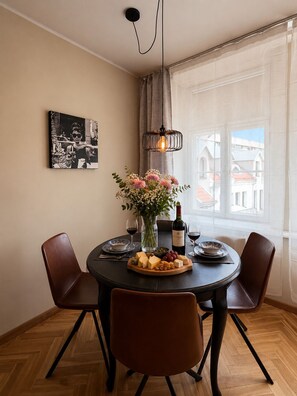 Ein Essbereich mit einem runden Tisch, Stühlen, einer Blumenvase, einer Weinflasche und einem Schwarz-Weiß-Foto an der Wand.