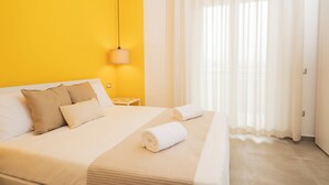 Habitación de hotel con cama, mesita de noche, lámpara y ventana con cortinas.