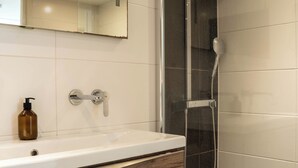Une salle de bain moderne avec une douche à parois de verre, un meuble-lavabo en bois et un lavabo blanc.