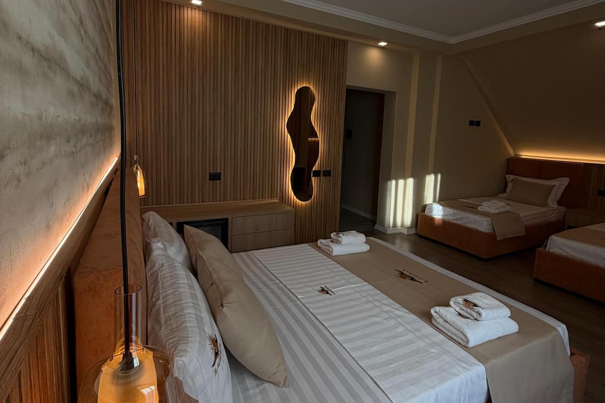 A modern hotel room with a large bed, a wooden accent wall, and a unique light fixture.