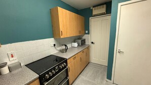 A kitchen with a stove, oven, microwave, and a white door. - Rest and Recover (West Bromwich)