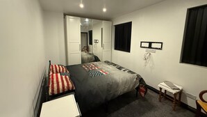 A bedroom with a bed, a desk, a chair, a wardrobe, and a mirror. - Rest and Recover (West Bromwich)
