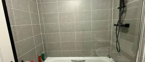 A bathroom with a bathtub, shower, and tiled walls.