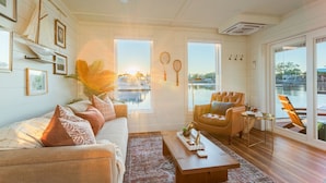 Amplia sala de estar con un gran ventanal con vista a un puerto deportivo, un sillón de cuero y una mesa de centro.