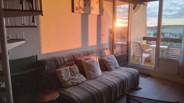 Habitación con sofá, una silla, una mesa y vistas al exterior.