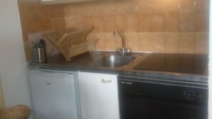 Cocina compacta con refrigerador, lavavajillas y estufa.