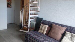 Una habitación con una escalera de caracol, un sofá estampado y un radiador.