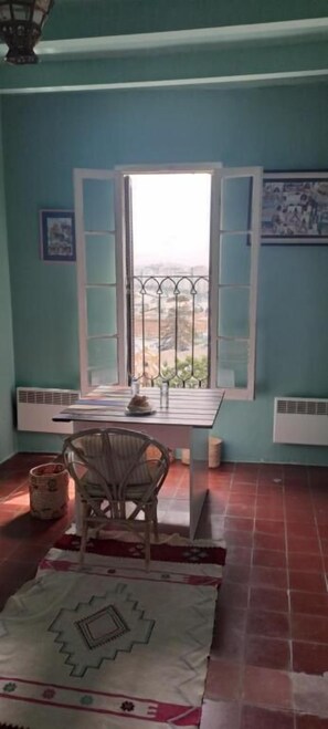 A room with a table, chair, window, and radiator.