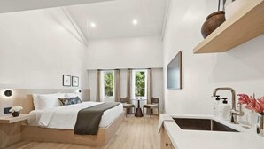 Quarto de hotel moderno com cama, mesa de cabeceira, escrivaninha, cadeira e pia.