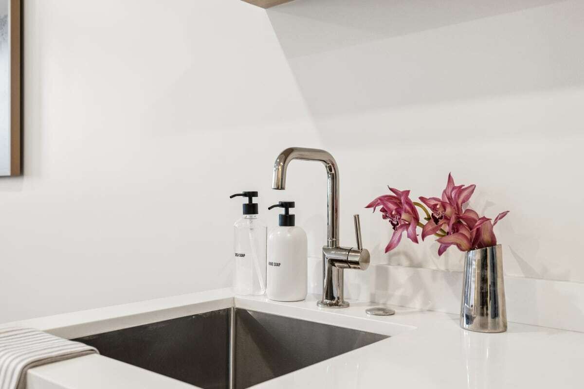 Une salle de bain avec un lavabo blanc, un robinet moderne et deux distributeurs de savon.