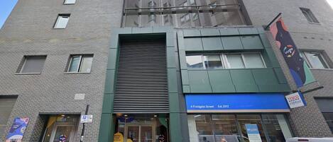 A building with a modern facade, a Tesco Express store, and a sign for a parking area.