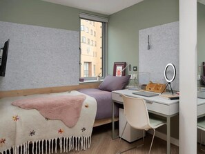 Ein Schlafzimmer mit einem Bett, einem Schreibtisch, einem Stuhl, einem Fenster und einer Wanduhr.