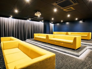 Ein Kino mit gelben Sitzen und einer dunkelblauen Wand.