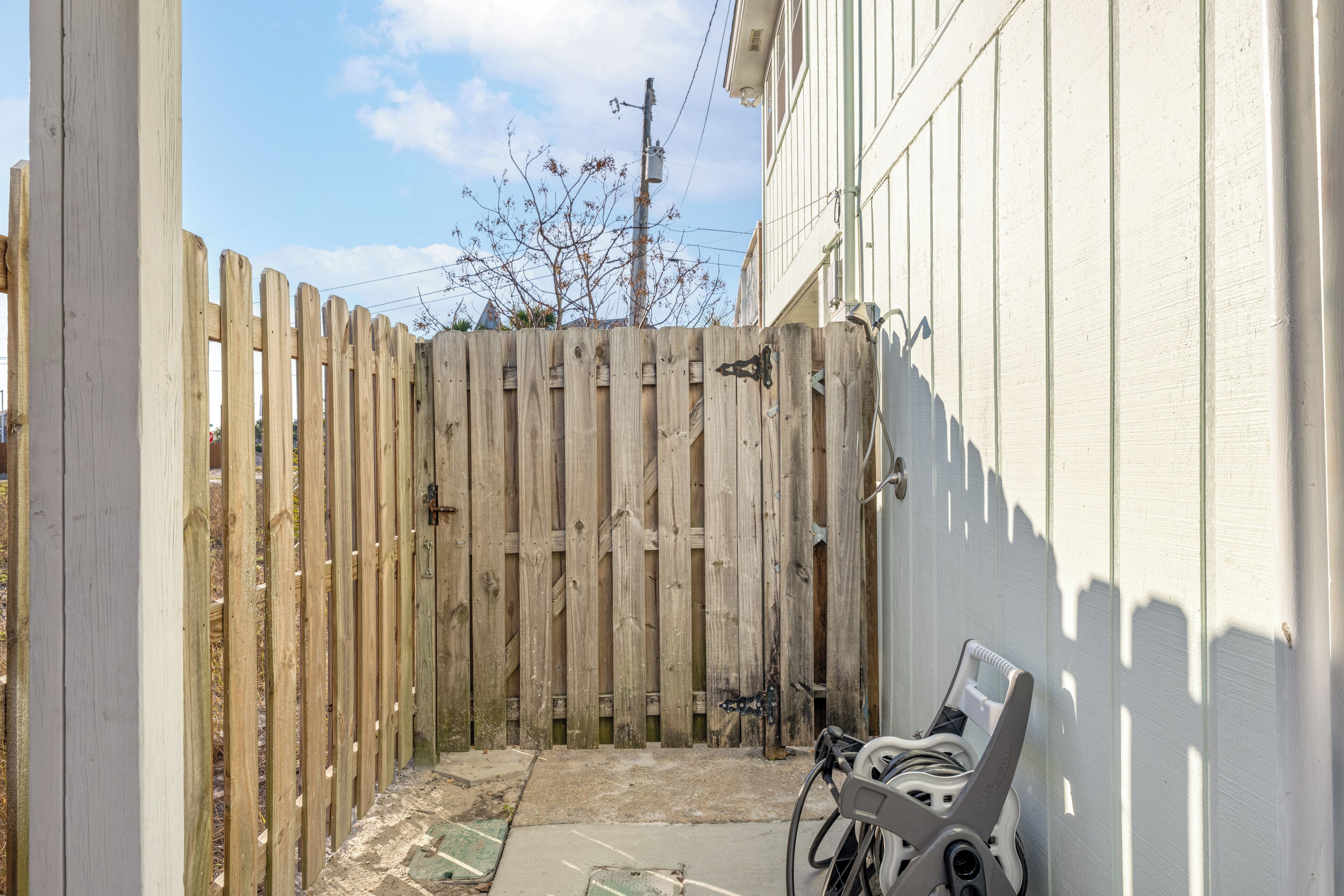 Une clôture en bois, un vélo et un bâtiment à la façade blanche.