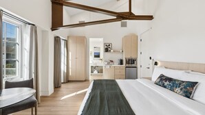 Een moderne hotelkamer met een groot bed, een bureau en uitzicht op de keuken en eetruimte.