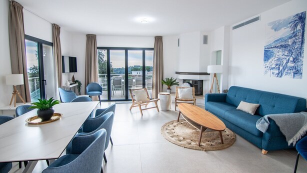 Ein modernes Wohnzimmer mit Essbereich, einem blauen Sofa und einem Kamin.