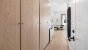 Eine moderne Küche mit integrierten Geräten, ein Essbereich mit Tisch und Stühlen sowie ein Flur mit Holztüren.